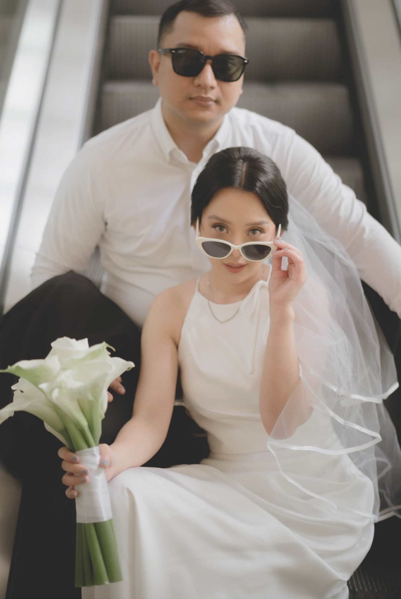 Pasangan mengenakan busana putih dalam sesi prewedding